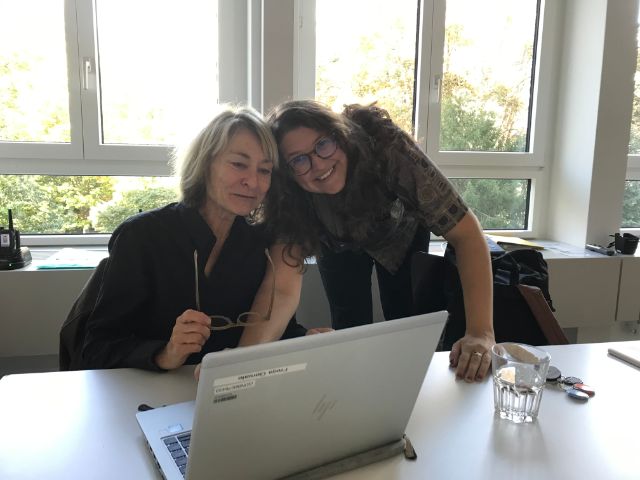 Zwei Frauen sind lächelnd vor einem Computerbildschirm vertieft